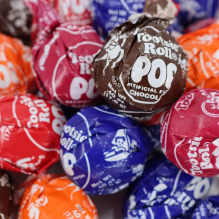 Close-up of Tootsie Roll Pop candies in various colors with visible branding.