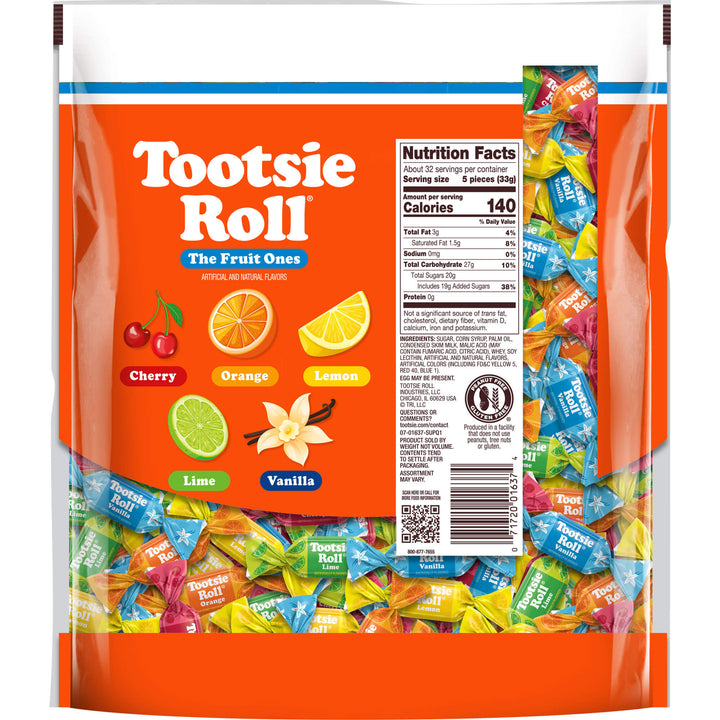 A large bag of Tootsie Roll 'The Fruit Ones' candy mix, showing a bright orange front label with illustrations of cherries, orange, lemon, lime, and vanilla, alongside a clear window displaying colorful individually wrapped candies inside.